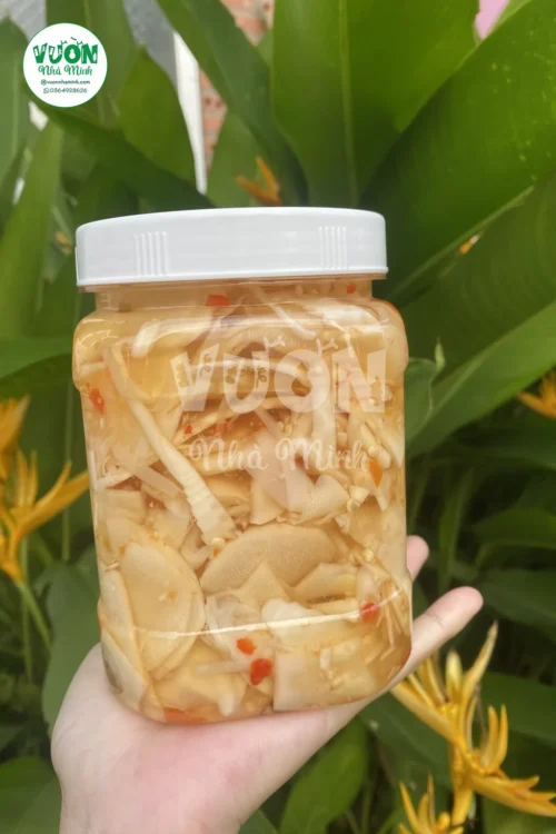 Măng ngâm chua ngọt gồm lát mỏng xen sợi, ớt đỏ và tỏi trong nước ngâm vàng nhạt